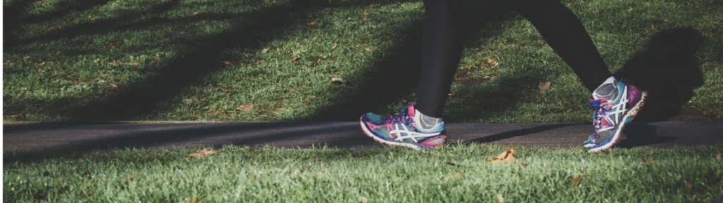 スニーカーを履いて公園を散歩している女性の足元の画像